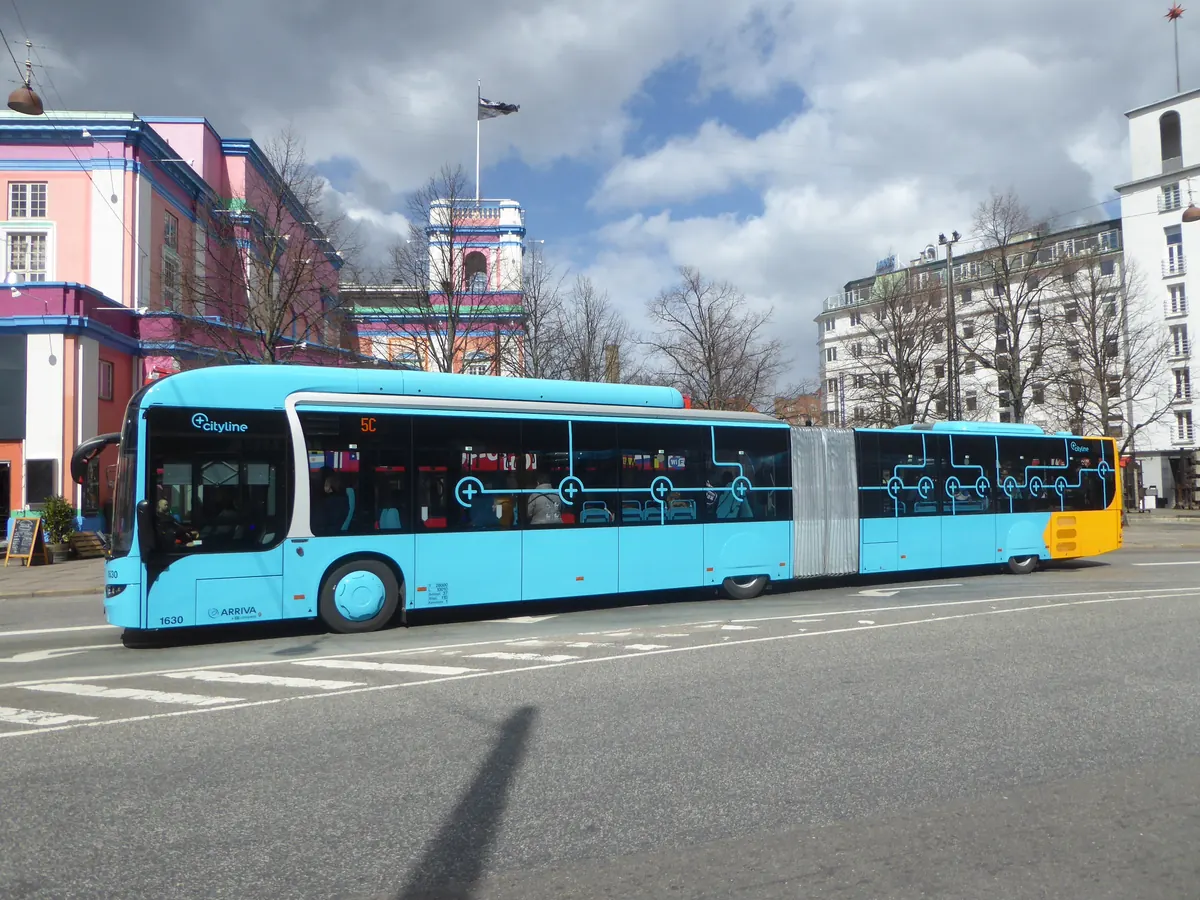 Blå leddbuss fra Movia ved en holdeplass i København en solrik dag