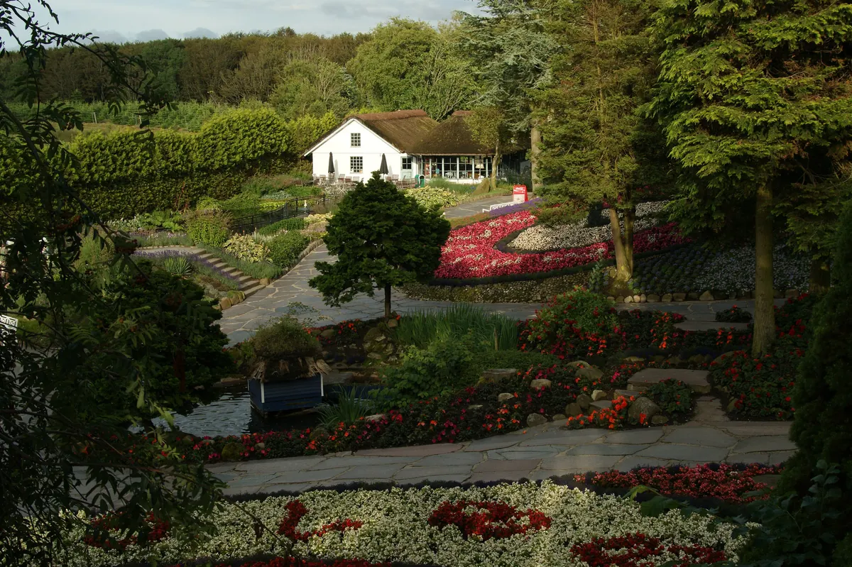 Blomsterbed og hage med et hvitt hus i bakgrunnen i Jesperhus på Mors