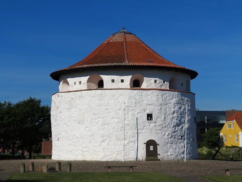 Det runde, hvitkalkede Krudttårnet med rødt tegltak under blå himmel i Frederikshavn