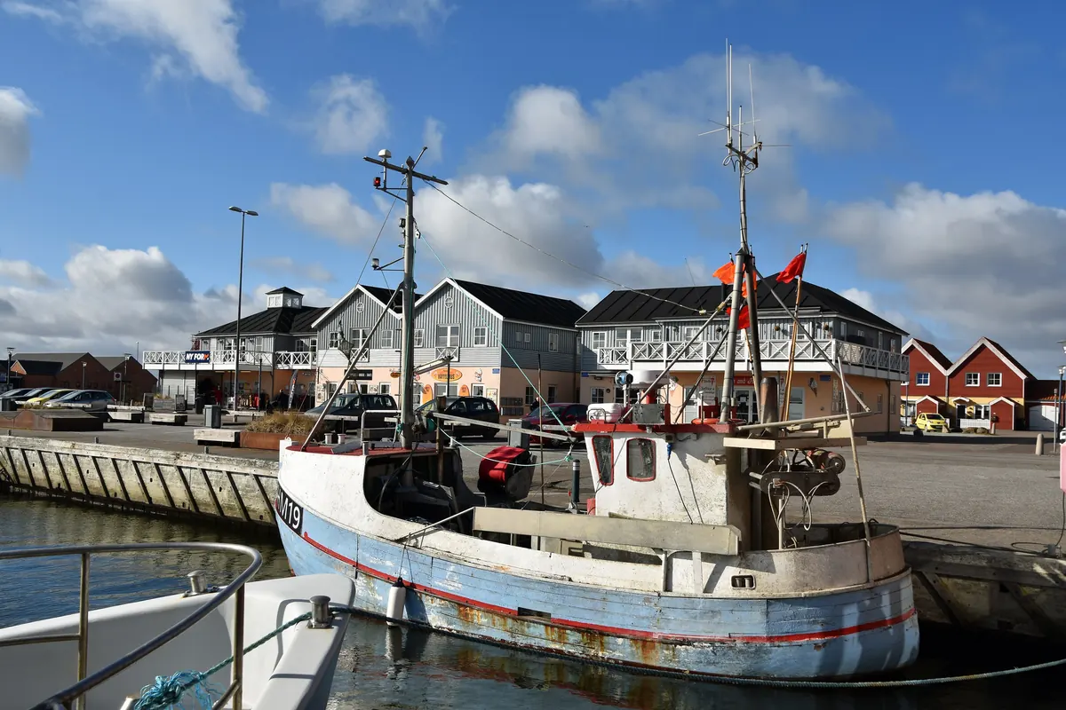Fiskebåt ved kaien i Hals havn med røde og hvite hus i bakgrunnen