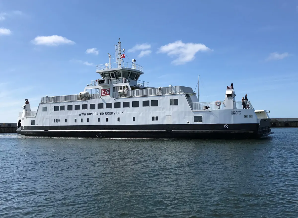Hvit bilferje til Rørvig ved kaien i Hundested havn under blå himmel