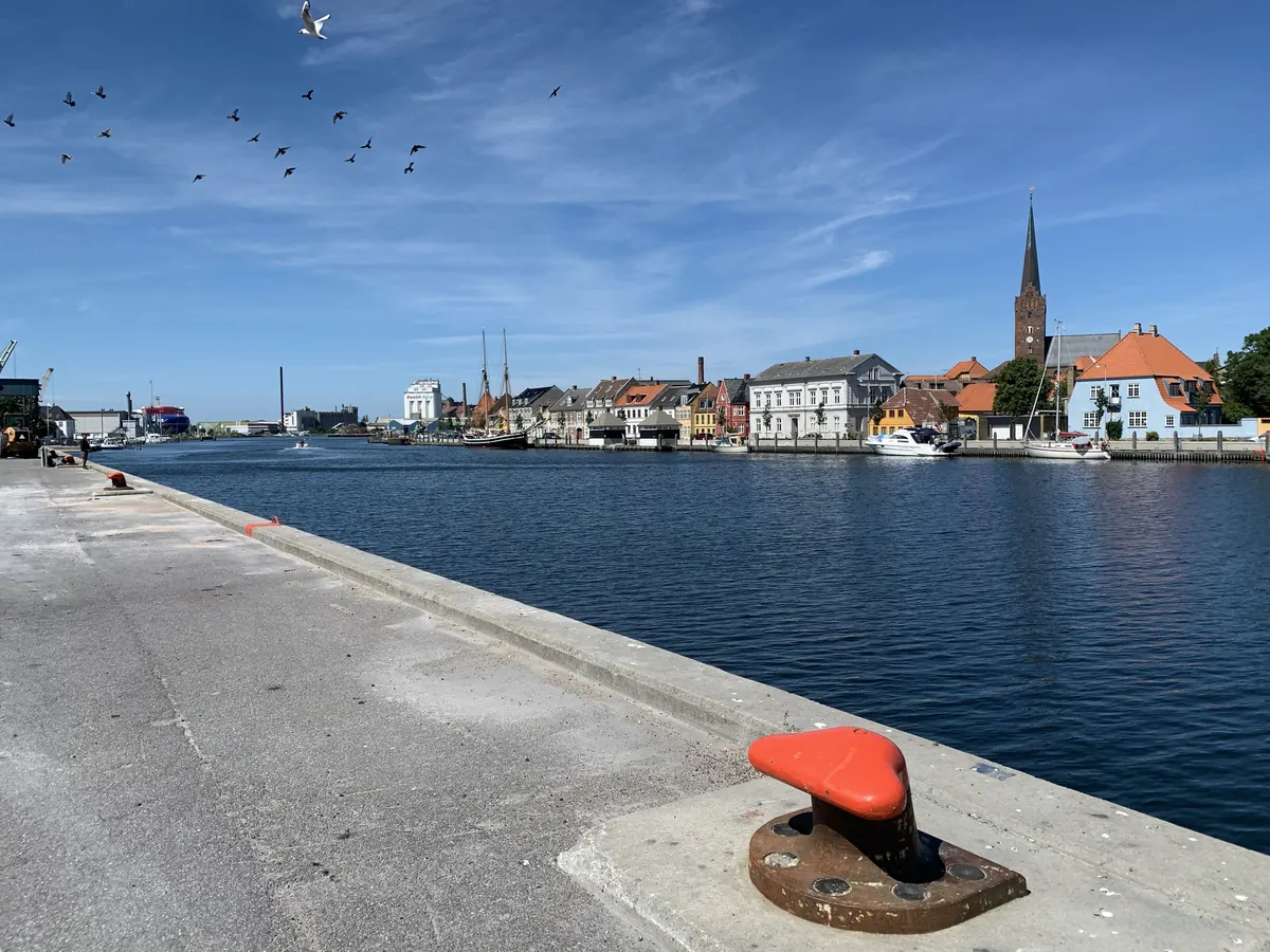 Havnekanalen i Nakskov med kirketårnet og bybebyggelsen i bakgrunnen under blå himmel