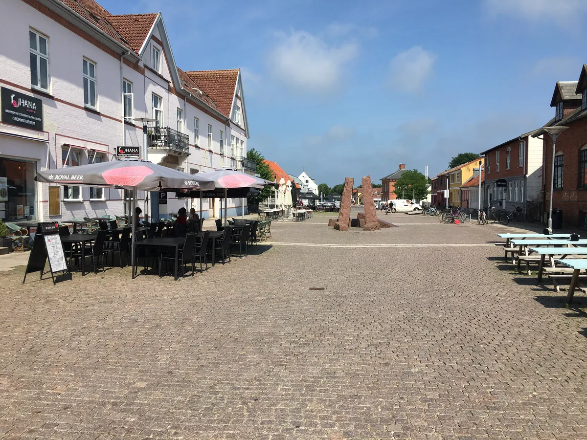 Brosteinsbelagt gågate med uteserveringer og parasoller i Nykøbing Sjælland en sommerdag