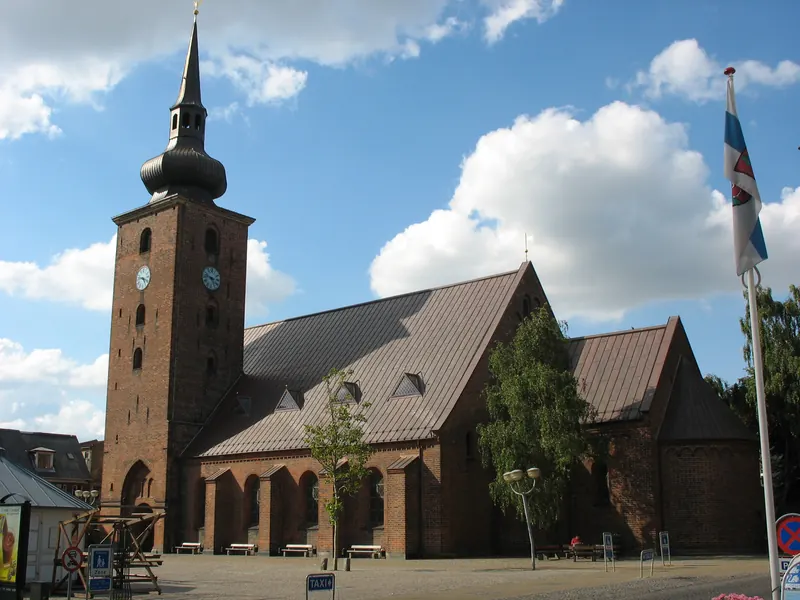 Vor Frelsers kirke i Horsens med rødt teglsteinstårn og løkformet spir under blå himmel