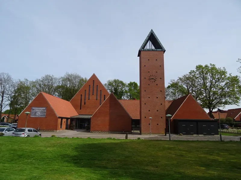 Fredens Kirke i Herning med røde teglgavler og frittstående klokketårn bak en grønn plen