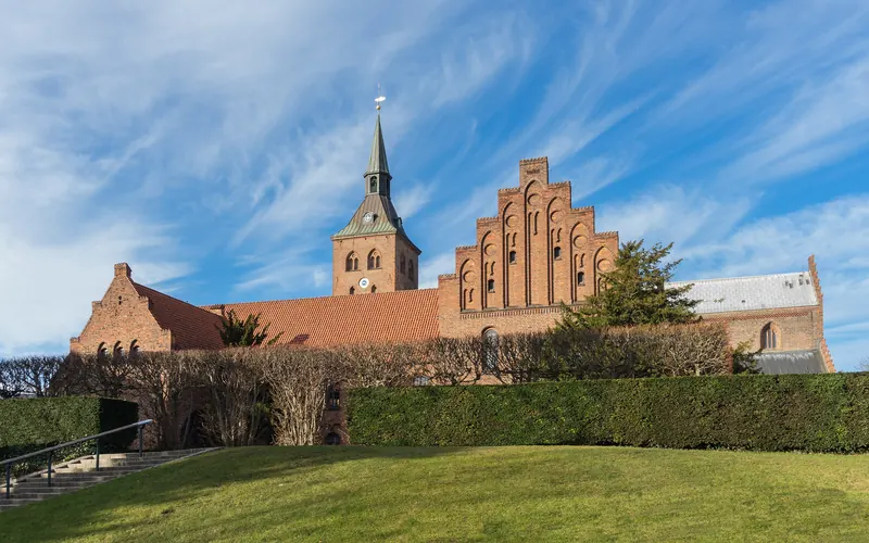 Sankt Knuds kirke i Odense sett fra en gressplen med trappegavler og tårn