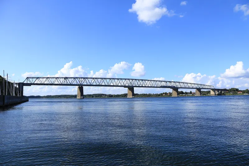 Den gamle Lillebæltsbroen over blått vann sett fra havna i Middelfart