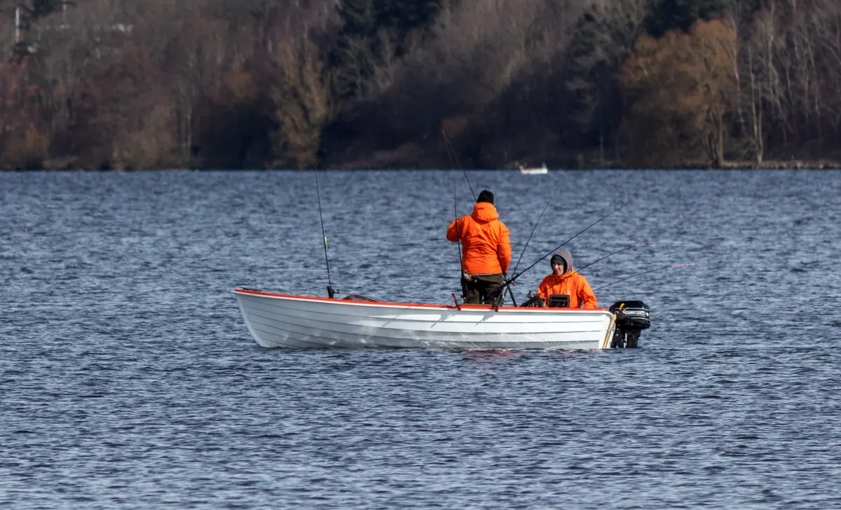 To sportsfiskere i en liten motorbåt på en innsjø omkranset av skog