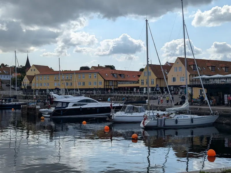 Seilbåter og motorbåter i havna i Svaneke med gule hus i bakgrunnen