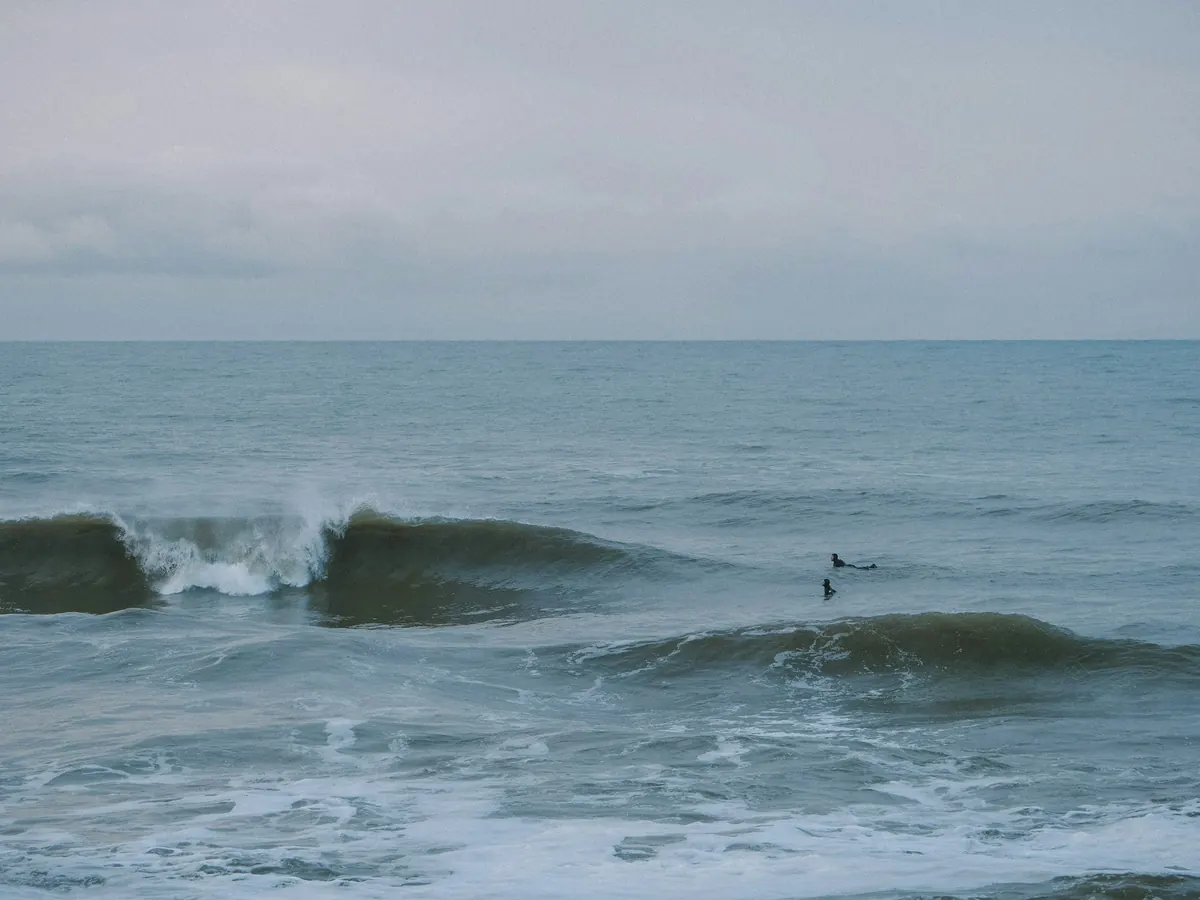 Surfer i bølgene utenfor Vorupør en grå dag