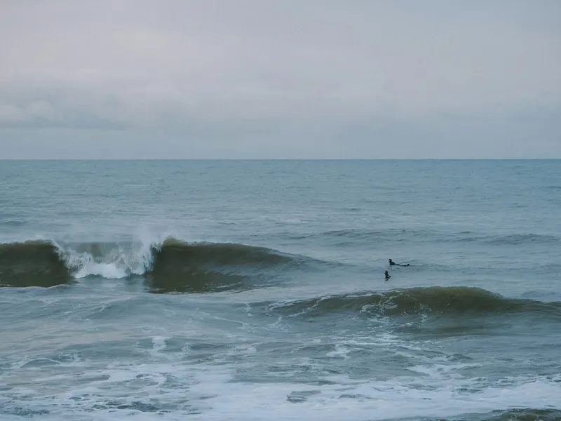 Surfer i bølgene utenfor Vorupør en grå dag