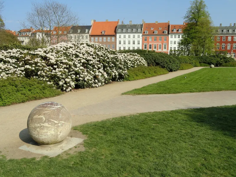 Blomstrende busker, gressplen og fargerike bygårder i kanten av Kongens Have i København