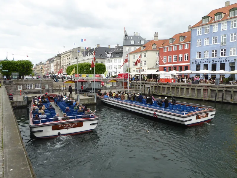Åpne kanalrundfartsbåter med passasjerer i Nyhavn, med fargerike hus langs kaien