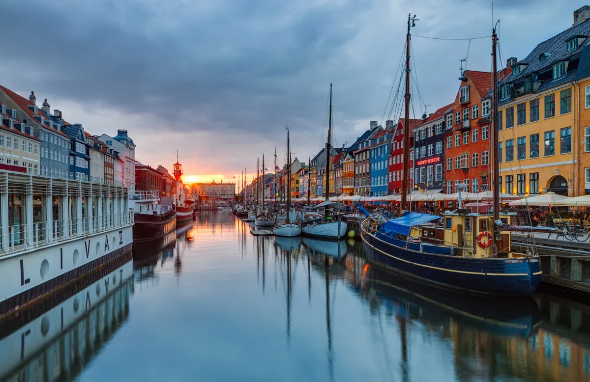 Fargerike hus og gamle seilskuter langs kanalen i Nyhavn i solnedgang