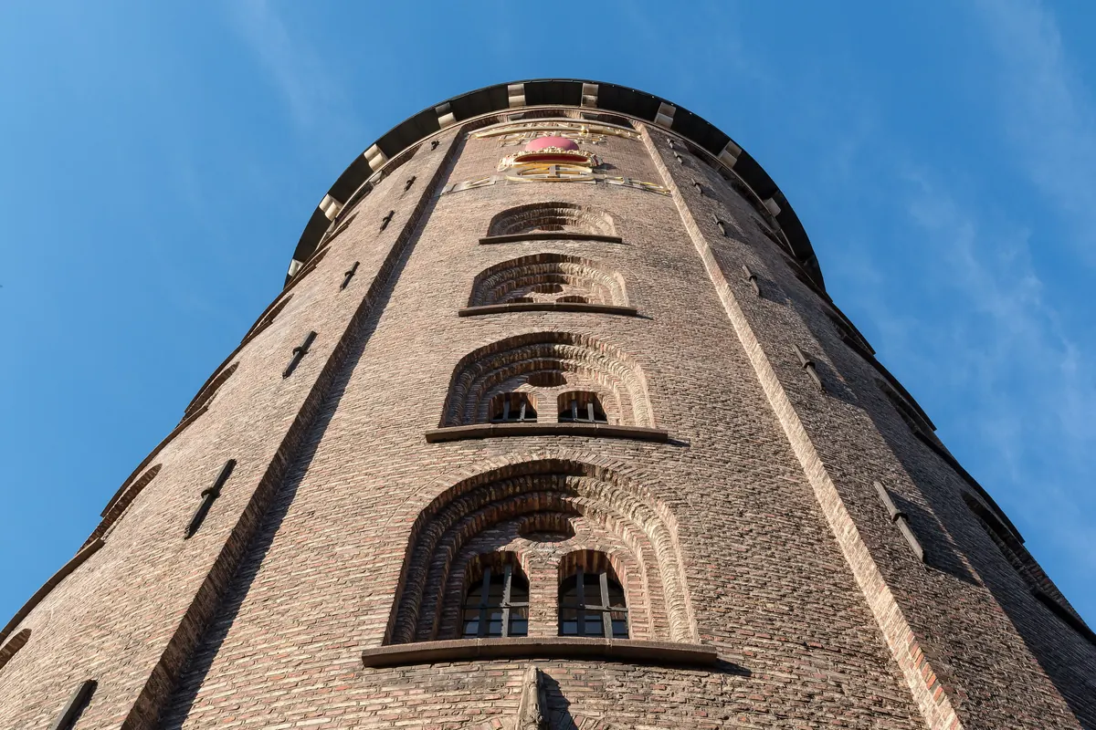 Rundetårn i gul tegl sett nedenfra mot blå himmel