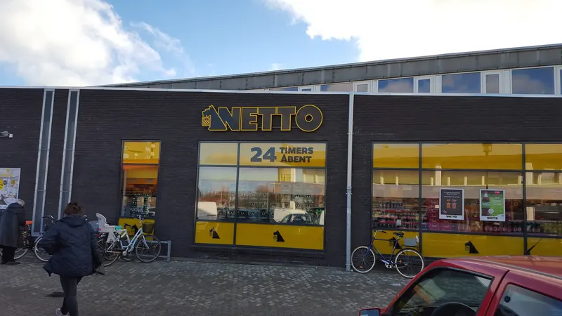 Døgnåpen Netto-butikk med gule vinduer og sykler utenfor på Tårnby ved København
