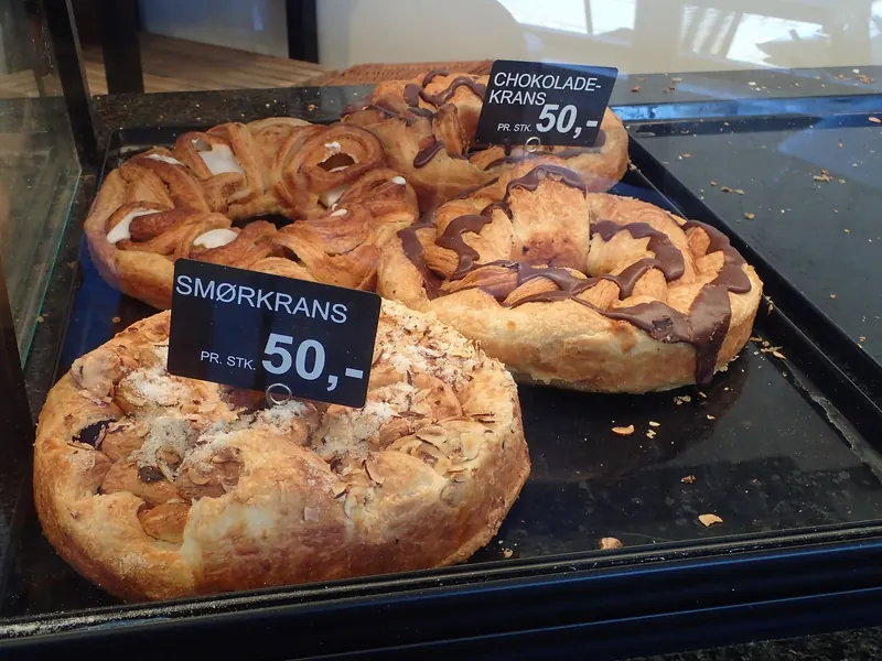 Smørkranser og sjokoladekranser med prisskilt i disken hos en dansk baker