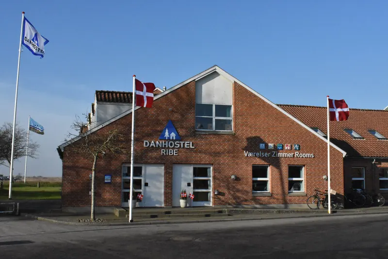 Rød murbygning med Danhostel-skilt og dannebrogsflagg foran vandrerhjemmet i Ribe