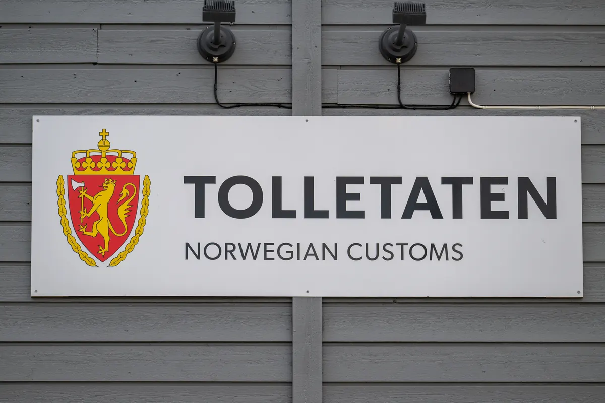 Skilt med Tolletatens logo og teksten Norwegian Customs på en trevegg