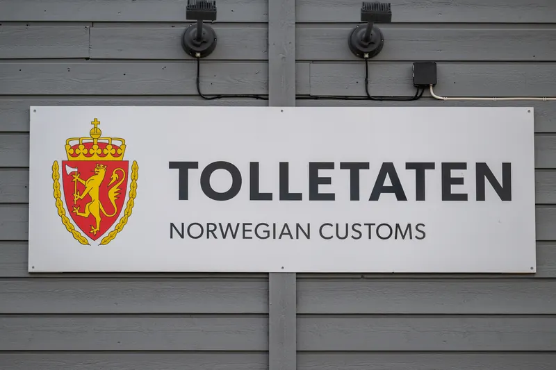 Skilt med Tolletatens logo og teksten Norwegian Customs på en trevegg