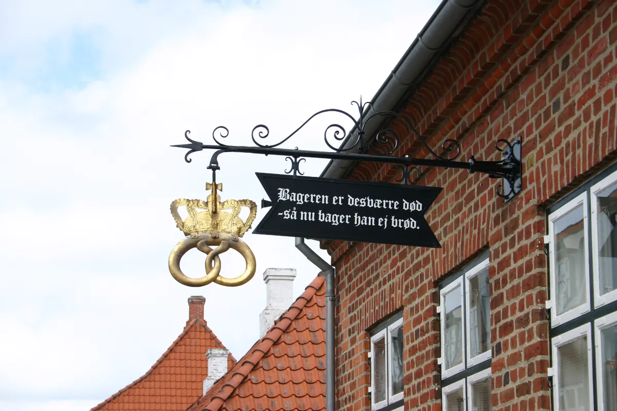 Gammelt bakerskilt med kringle og dansk tekst på en murvegg i Viborg