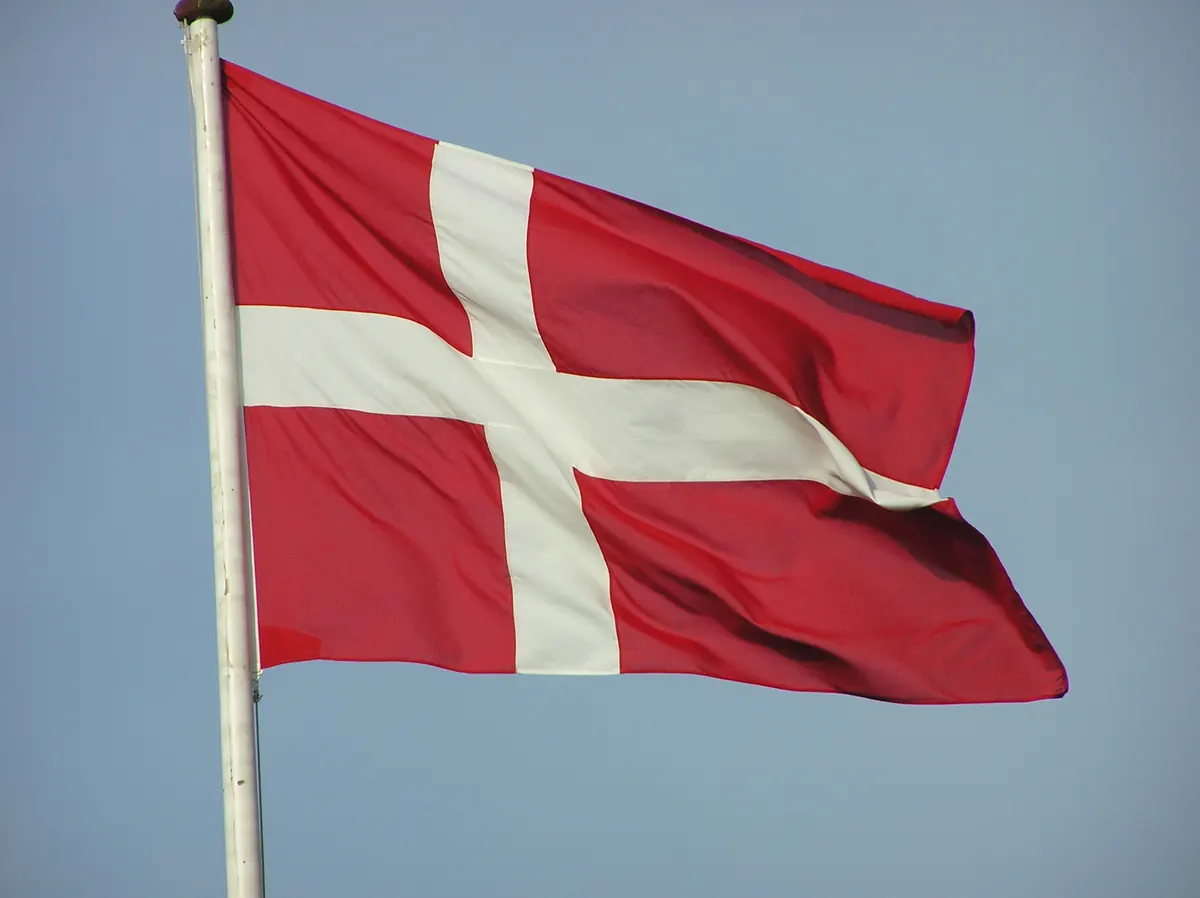Dansk flagg som vaier fra en flaggstang mot blå himmel