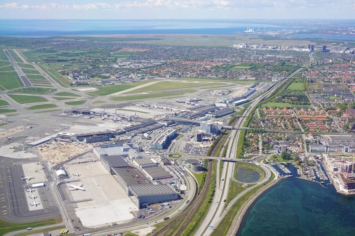 Københavns lufthavn med rullebaner og terminaler sett fra luften, med Øresund til høyre