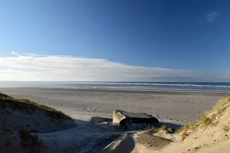 Gammel bunker i sanddynene ved en bred, lys strand i Blåvand
