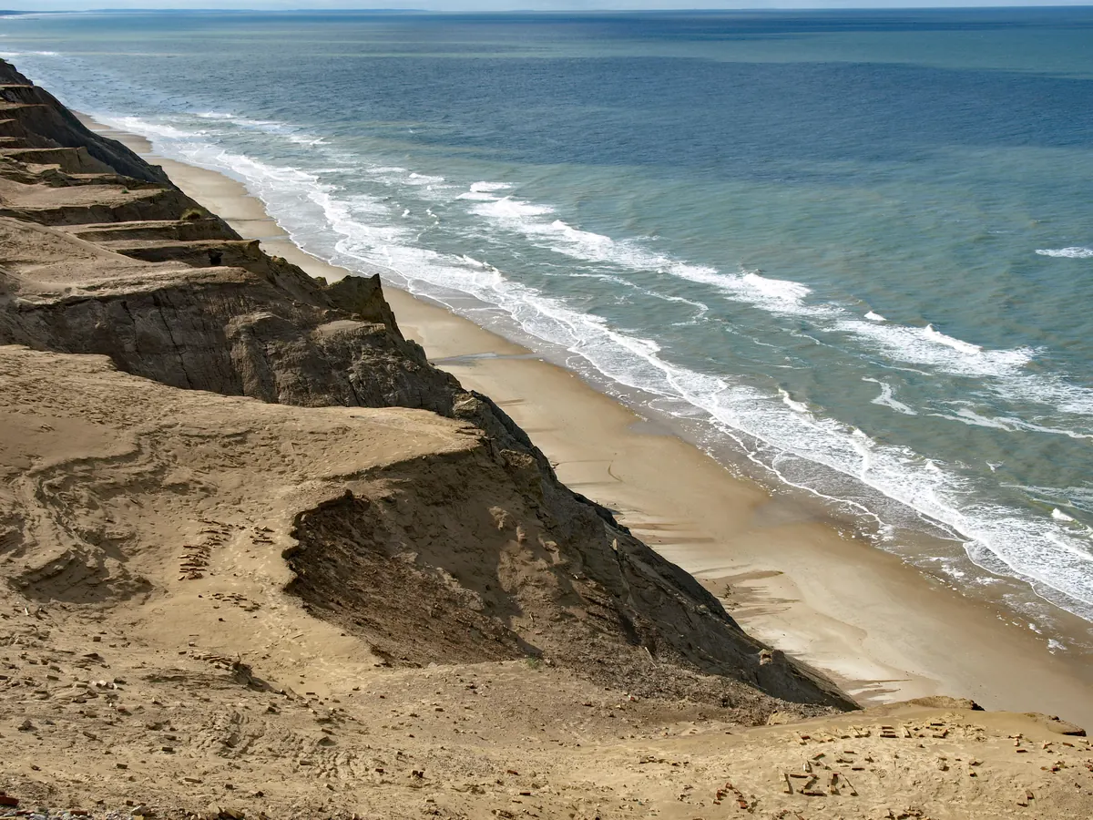 Høy sandskrent langs Lønstrup Klint med bølger som slår inn mot stranden
